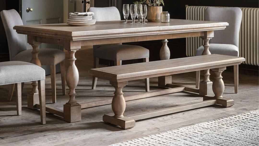 Wooden dining table with glasses and stacked plates with 4 matching dining chairs and dining bench 