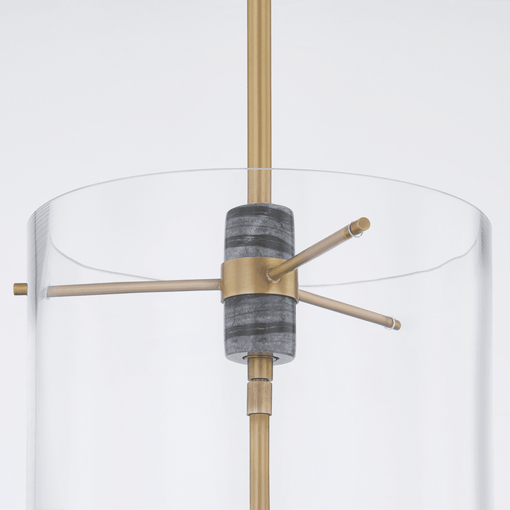 The Adonis Lantern Light - Brass features a modern lantern silhouette with a cylindrical clear glass shade, Vintage Brass rod and accents, and a central gray textured element, photographed against a plain white background.