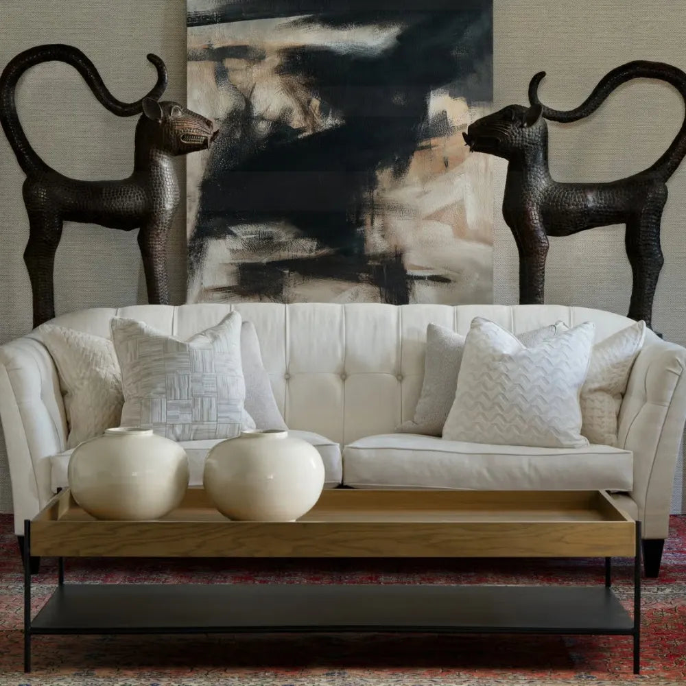 White sofa with decorative pillows in a room with abstract art and sculptures.