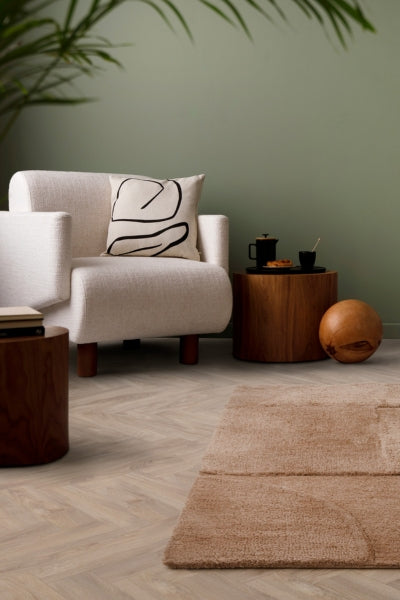 Modern living room with a white armchair, wooden coffee table, and decorative items.