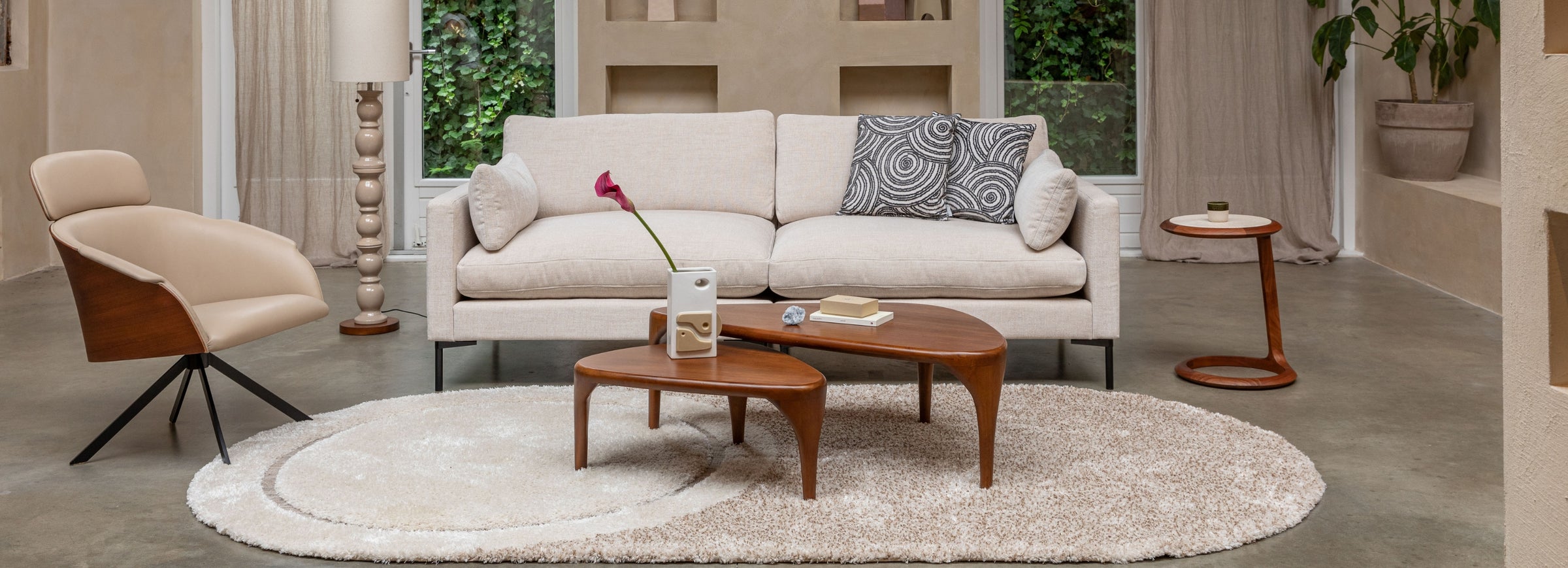 Modern living room with beige sofa, armchair, and coffee table on a light gray rug.