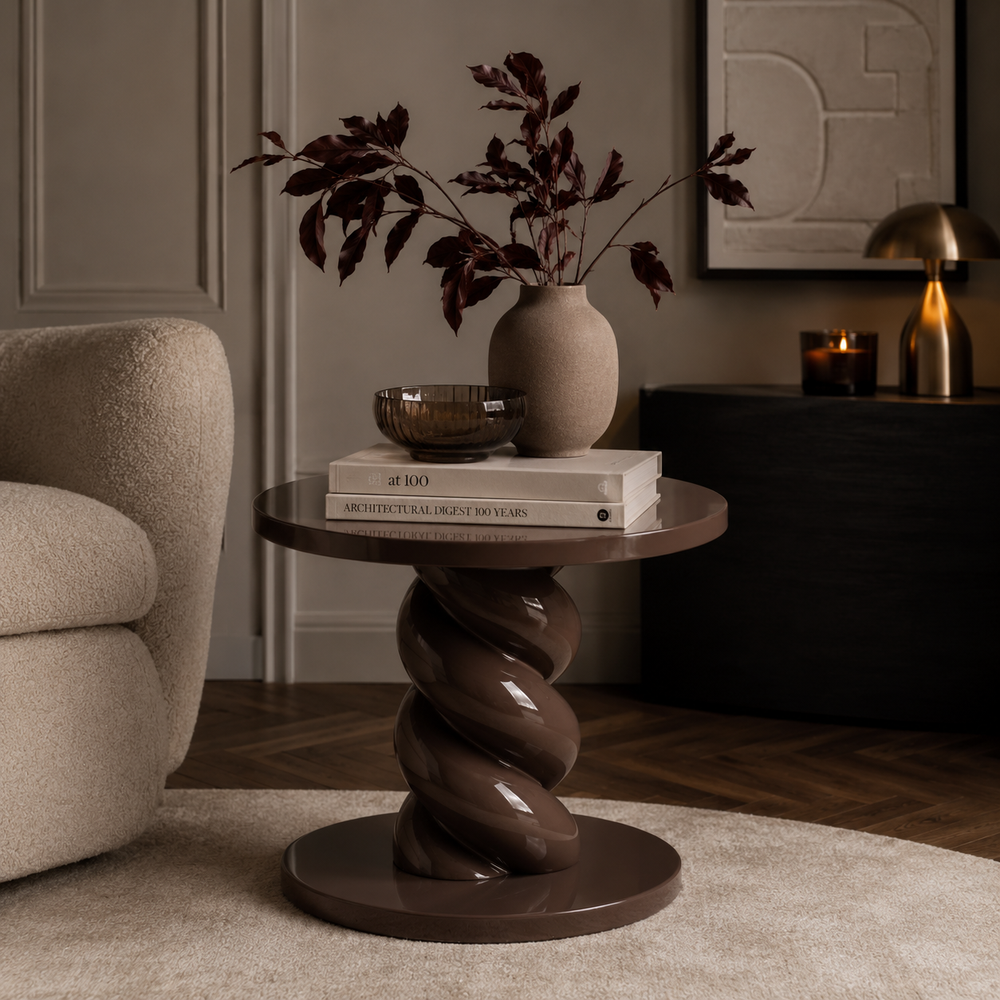 A round side table with a glossy dark brown spiral pedestal base, styled in a living room setting with a ceramic vase, books, and a bowl on top.