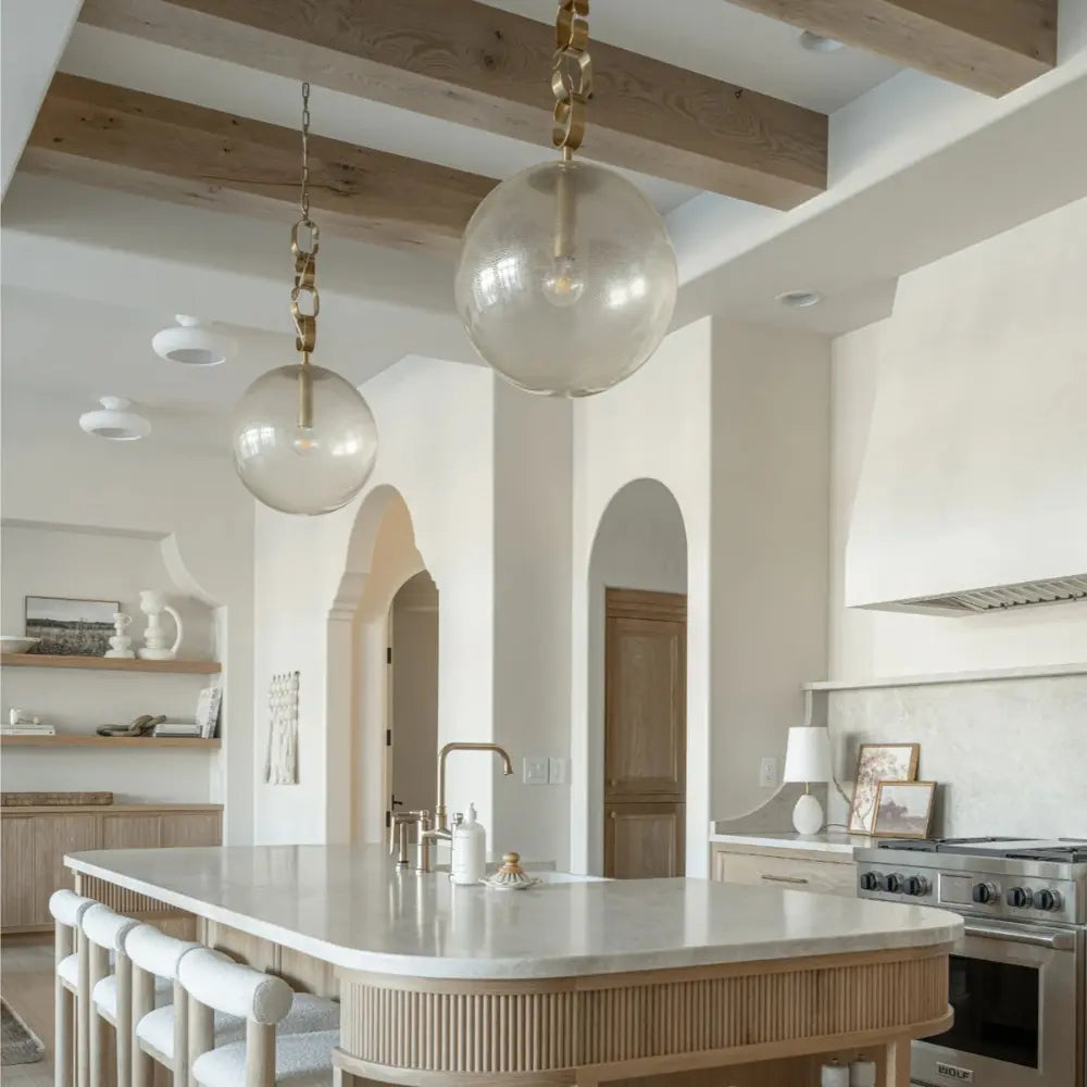 Modern kitchen with island, pendant lights, and white walls.
