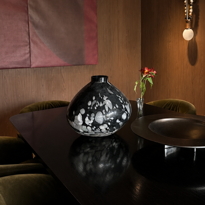 Dining room with a dark table, vase, and wall art in a warm-toned room.