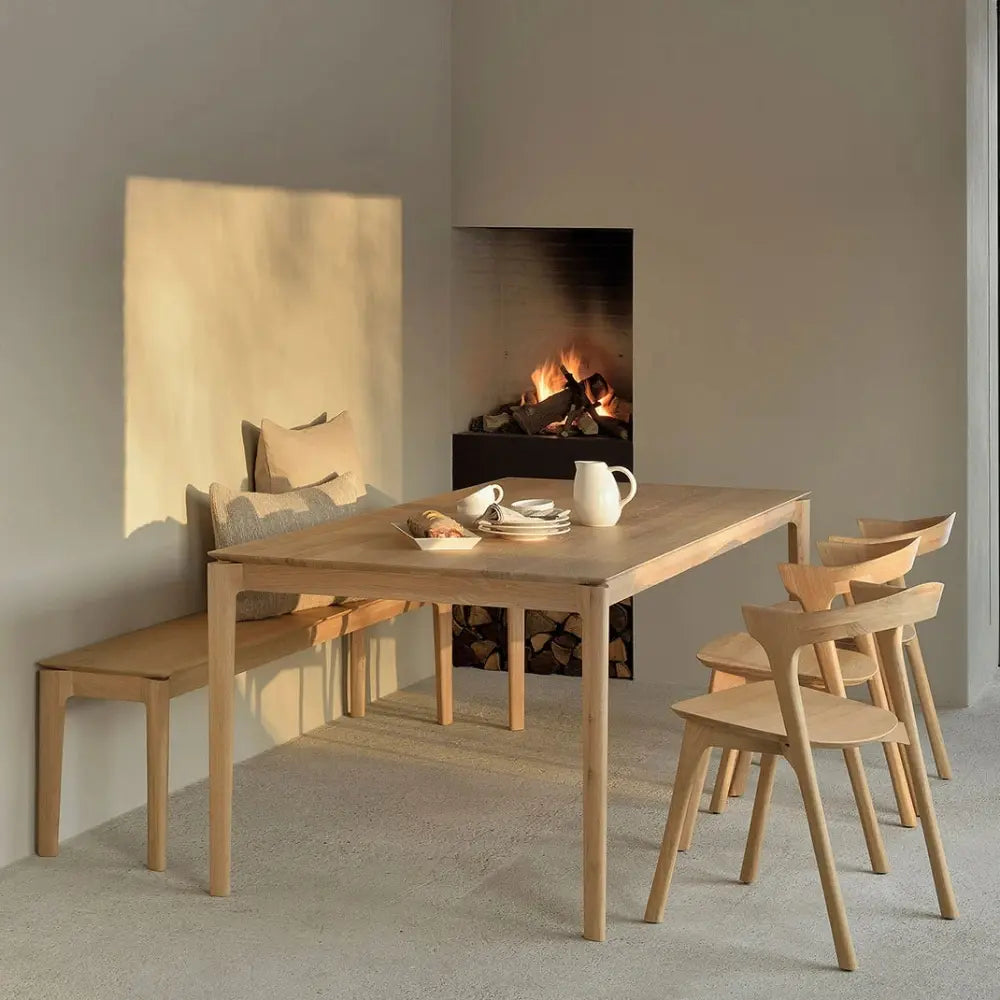 Wooden dining table with chairs in front of a fireplace in a room.