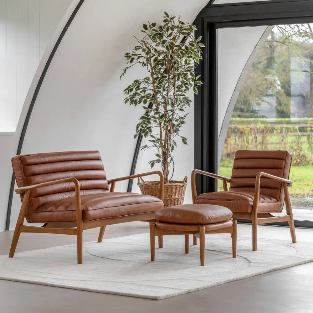 Brown leather armchairs with ottoman in a modern living room setting.