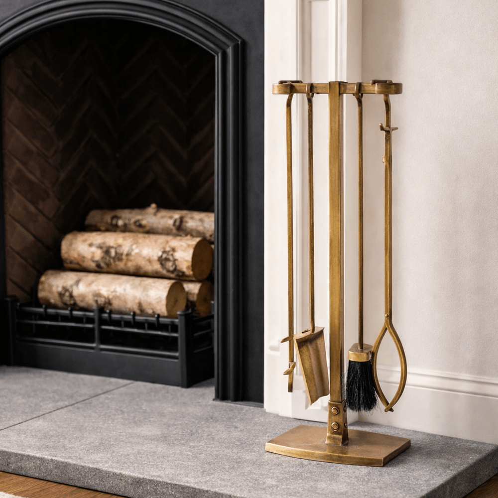 Gold fireplace tools against a white wall with a fireplace in the background