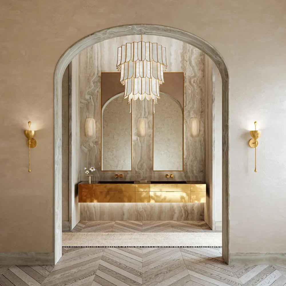 Luxurious bathroom with a large arched mirror, gold fixtures, and wall sconces.