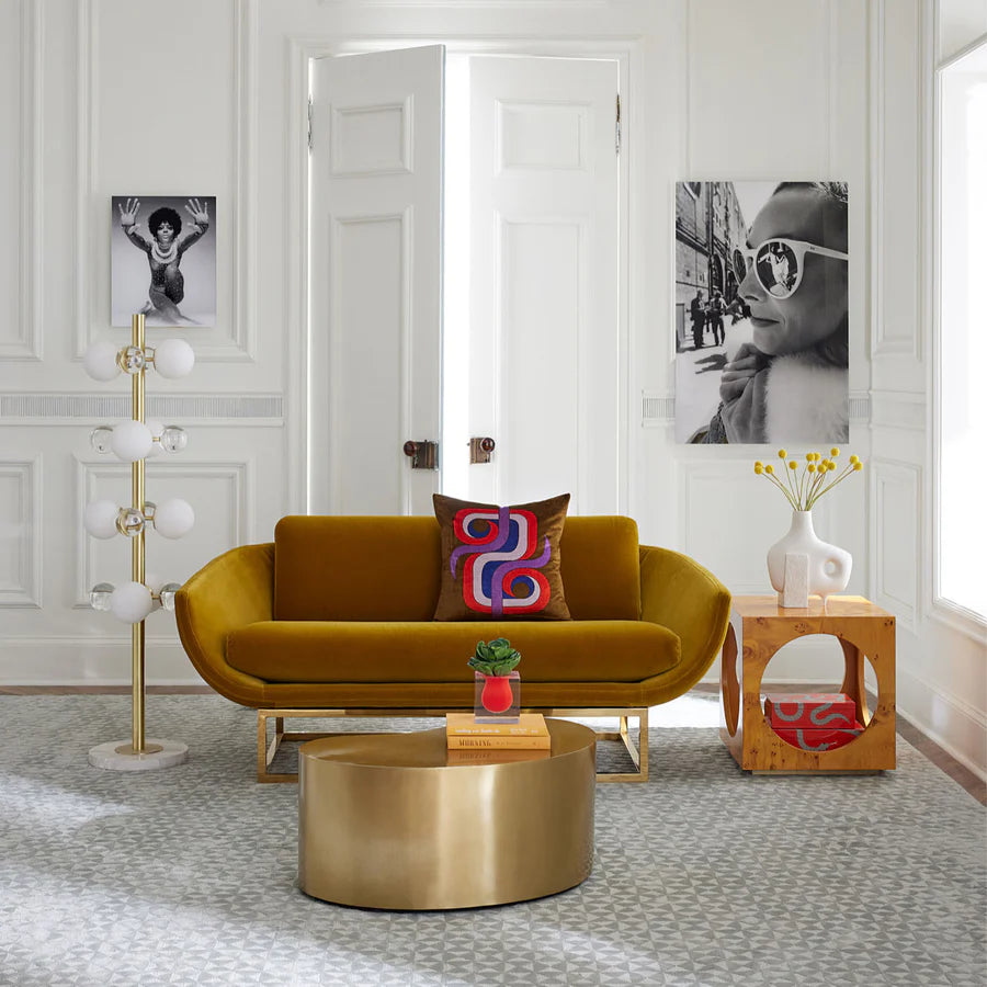 Mustard velvet sofa in a light bright room with gold coffee table and monochrome wall art. 