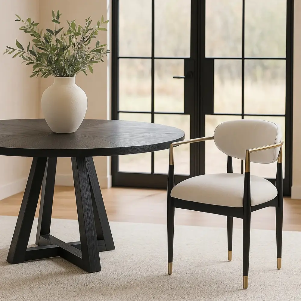 Dining table with a vase of greenery and a chair in a room with large windows.