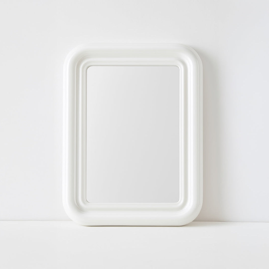 White mirror with curved edges on plain background