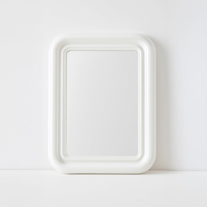 White mirror with curved edges on plain background