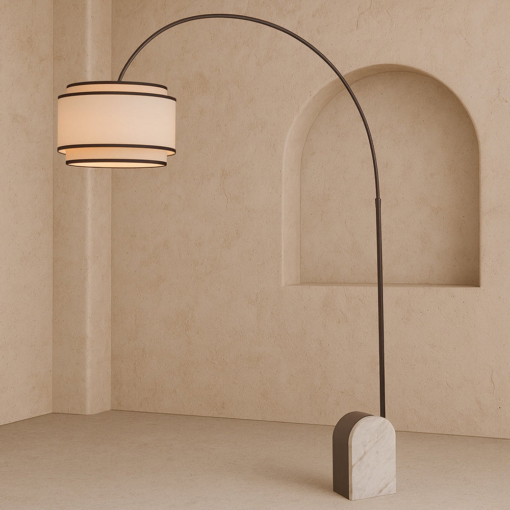Curved floor lamp with marble base and white shade with black contrast piping on a neutral background