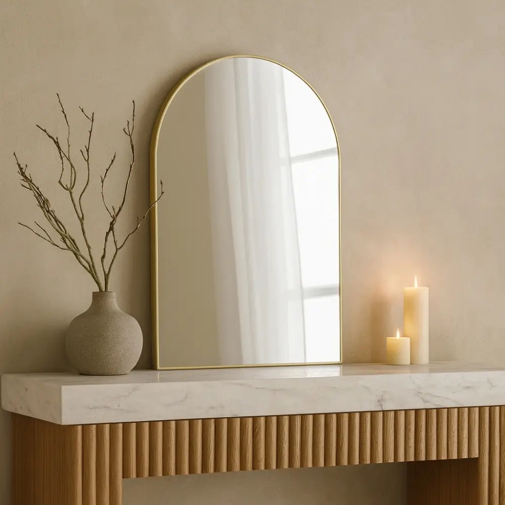 Decorative setup with a mirror, vase, and candles on a marble surface.