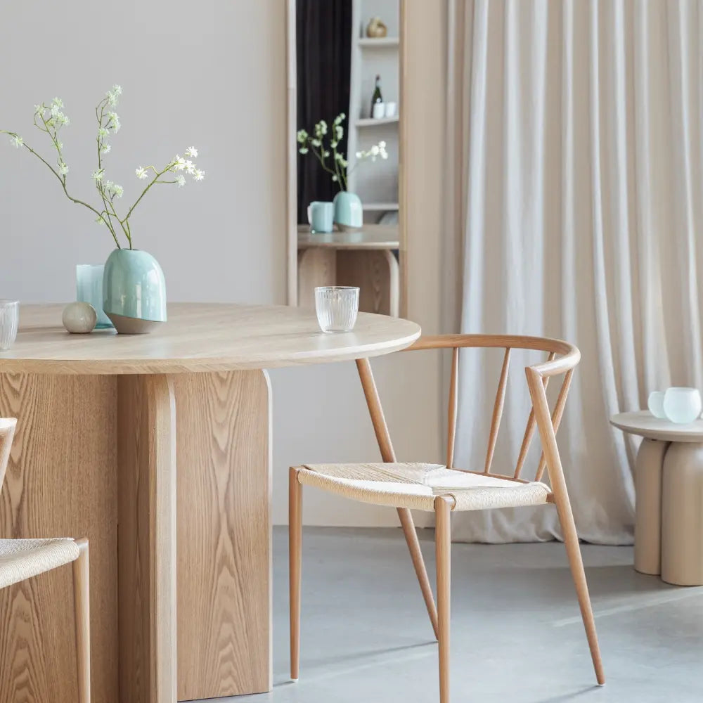 Dining area with wooden table and chair, light-colored walls, and neutral decor.