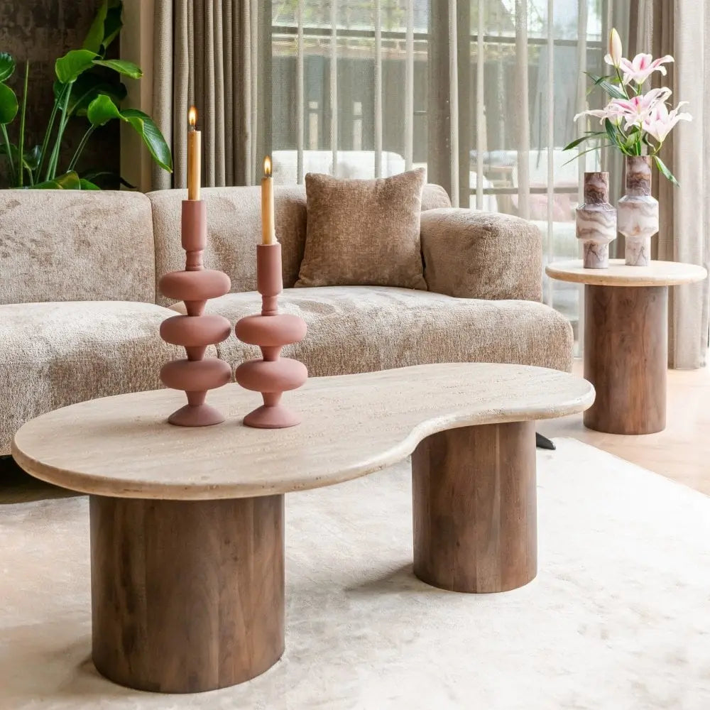 Travertine coffee table and side table set on dark brown base, set on a beige rug with a taupe velvet sofa.