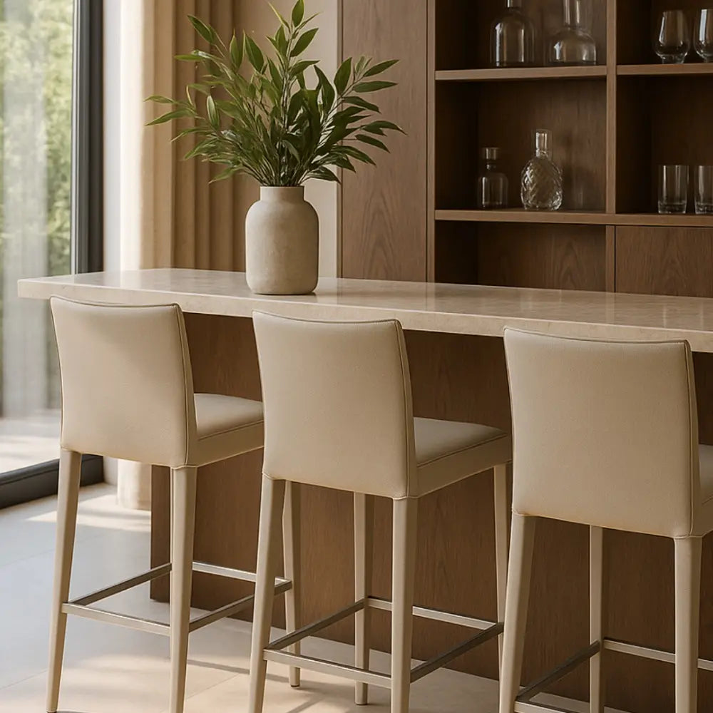 Dining area with a long table, bar stools, and a vase with plants.