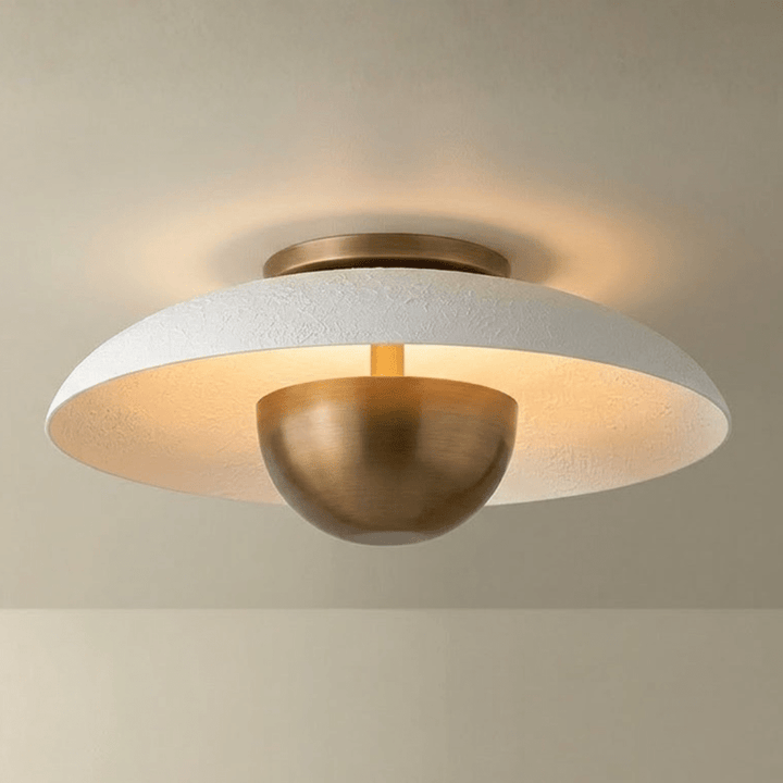 Ceiling light fixture with white textured shade and gold metal base on a beige background