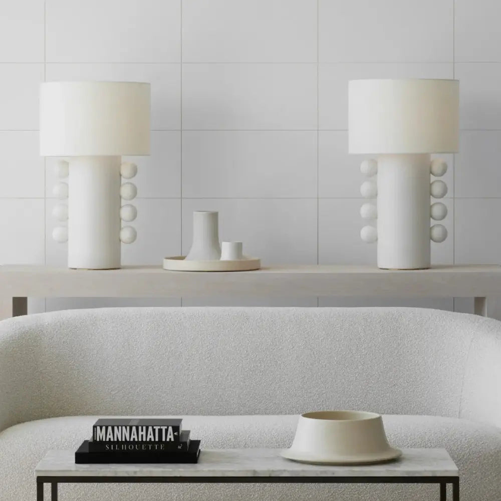 Large white ceramic lamps with soft linen shades against a living room backdrop