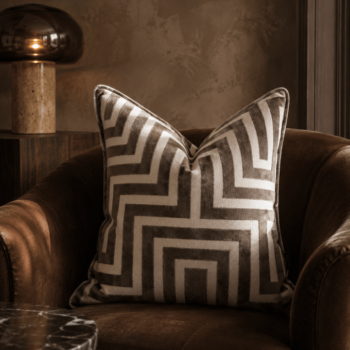 Decorative pillow with geometric pattern on a brown armchair