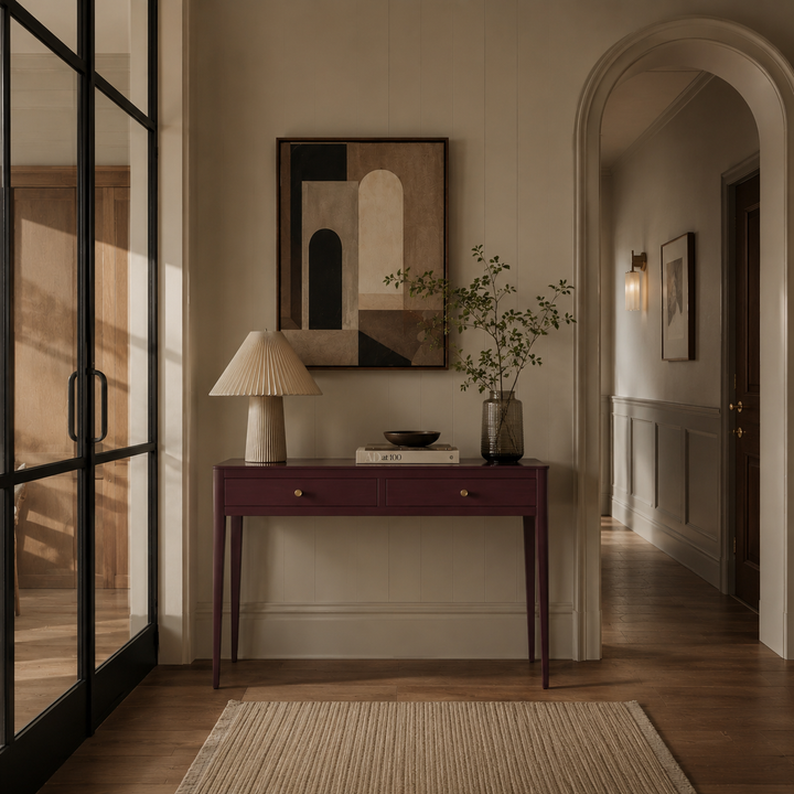 Modern interior with a console table, lamp, and abstract painting in a well-lit room.