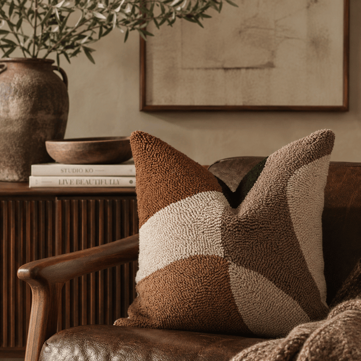Decorative pillows on a sofa with a vase and books in the background