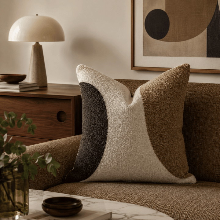 Decorative pillows on a couch with a lamp and abstract art in the background