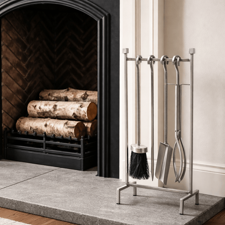 Fireplace with logs and a metal tool set on a stand.