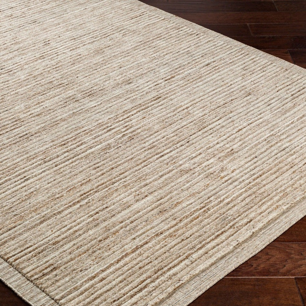 A close-up of the Yasmin Hand Knotted Rug - Natural shows its beige, textured surface with subtle horizontal stripes on a dark wood floor, bringing warmth and style to contemporary spaces and complementing modern furniture.