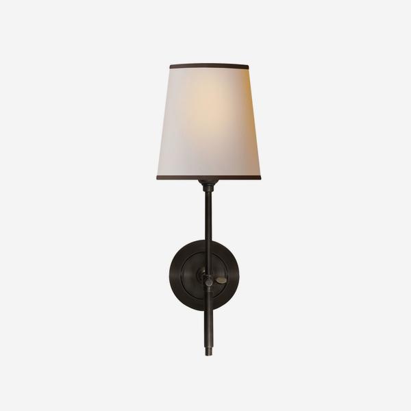 A small wall lamp in bronze with a natural shade which has a smart black trim